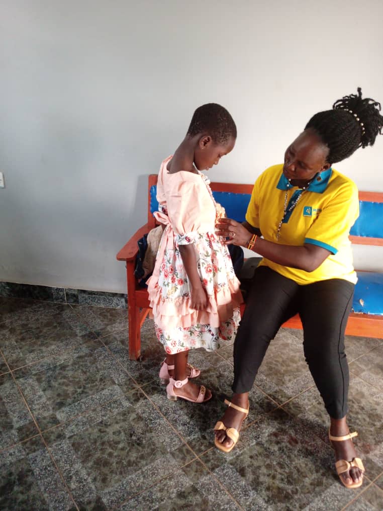 A child being supported during a clinic visit at Nsobani